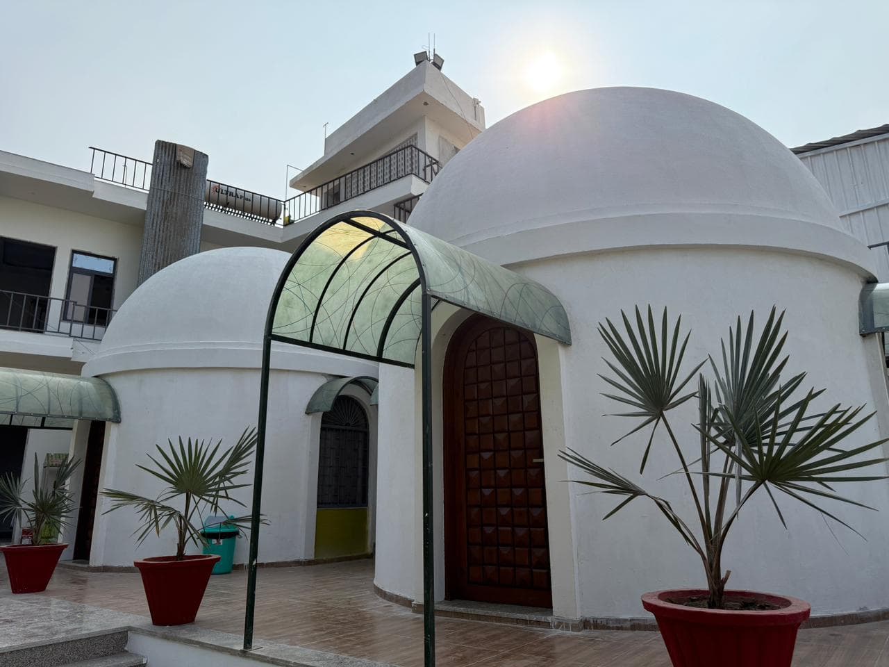 Dome cottage with carved door and palm plants